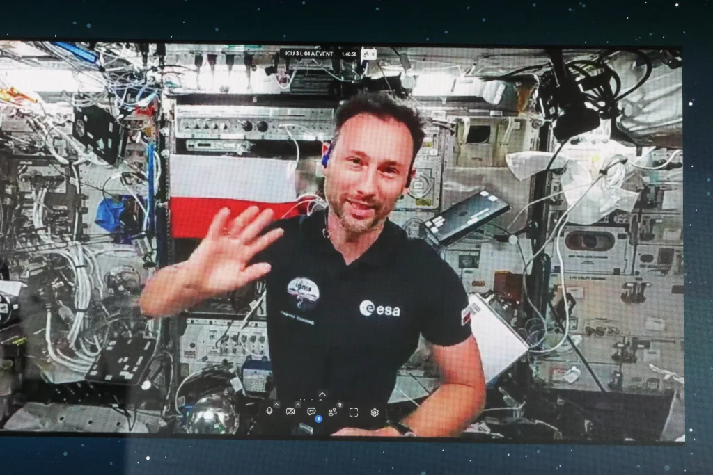 Łódź, 02.07.2025. Przebywający na Międzynarodowej Stacji Kosmicznej polski astronauta Sławosz Uznański-Wiśniewski (na ekranie) podczas połączenia wideo na żywo w EC1 w Łodzi, 2 bm. Podczas trwającego ok. 20 minut połączenia Sławosz Uznański-Wiśniewski wykonywał eksperymenty w stanie nieważkości oraz odpowiadał na pytania zadawane przez młodzież. (jm) PAP/Marian Zubrzycki