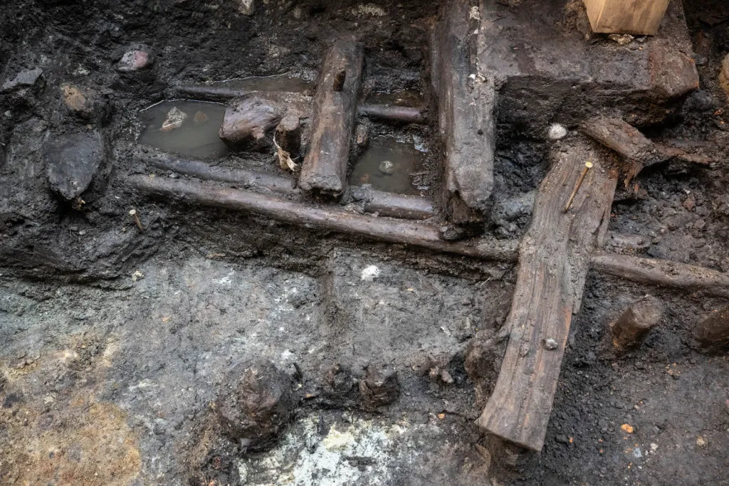 Toruń, 19.11.2025. Fragment nieznanych wcześniej drewnianych konstrukcji z XIII wieku, 19 bm. w Toruniu. Konstrukcje odkryte zostały podczas badań archelogocznych na dziedzińcu Domu Mikołaja Kopernika w Toruniu. To jedne z najstarszych takich znalezisk w mieście. Konstrukcje trafią do konserwacji i staną się elementem przyszłej wystawy stałej muzeum. (mr) PAP/Tytus Żmijewski