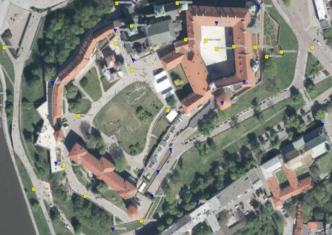 Obraz satelitarny krakowskiego Wawelu z zaznaczonymi elementami osnowy geodezyjnej - żółte kwadraty - osnowa pozioma i niebieskie trójkąty osnowa wysokościowa. Źródło: geoportal.gov.pl 
