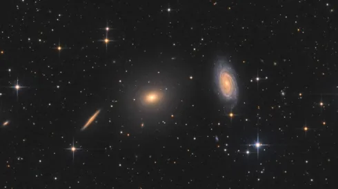 Na zdjęciu widać galaktykę eliptyczną NGC 5982 (w centrum) oraz galaktykę spiralną NGC 5985 (po prawej). Okazuje się, ze te dwa rodzaje galaktyk zachowują się inaczej w przypadku nadmiarowej grawitacji w swoich zewnętrznych rejonach. Źródło: Bart Delsaert (www.delsaert.com).