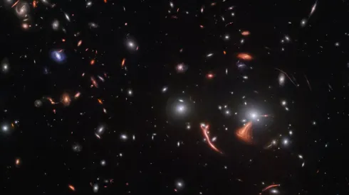 Soczekowanie grawitacyjne odległych galaktyk przez gromadę galaktyk SDSS J1226+2149. Obraz uzyskano przy pomocy Kosmicznego Teleskopu Jamesa Webba. Źródło: ESA/Webb, NASA &amp; CSA, J. Rigby.