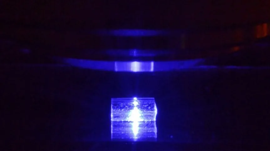 Pobudzany światłem niebieskim kryształ fluorku litu z zarejestrowanymi śladami cząstek jonizujących podczas obserwacji pod mikroskopem fluorescencyjnym. (Źródło: IFJ PAN)