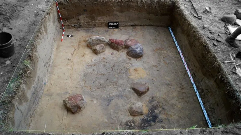 Grób z kamienną obstawa z widocznym w centrum pradziejowym wkopem. Źródło: Centrum Promocji i Informacji Uniwersytet Mikołaja Kopernika